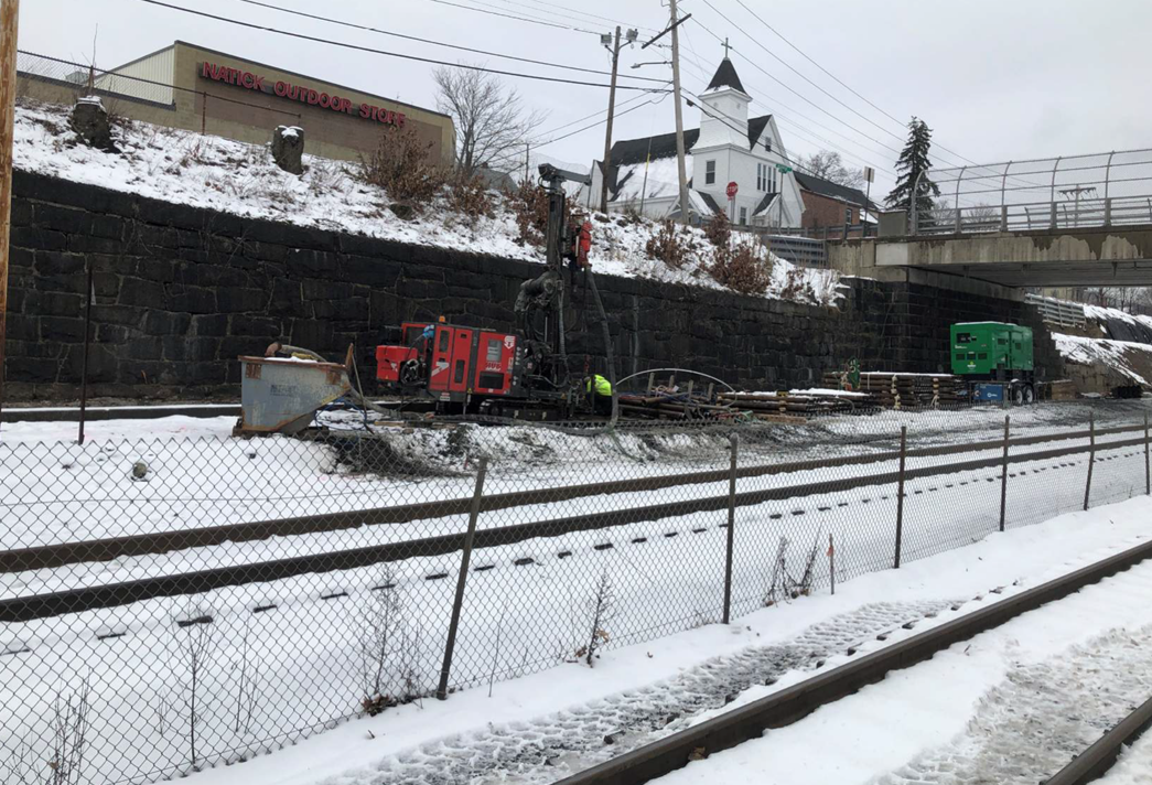 The outbound Natick track west of Washinton Bridge, shown covered in snow. Various construction equipment and materials are shown lined up on the side. 