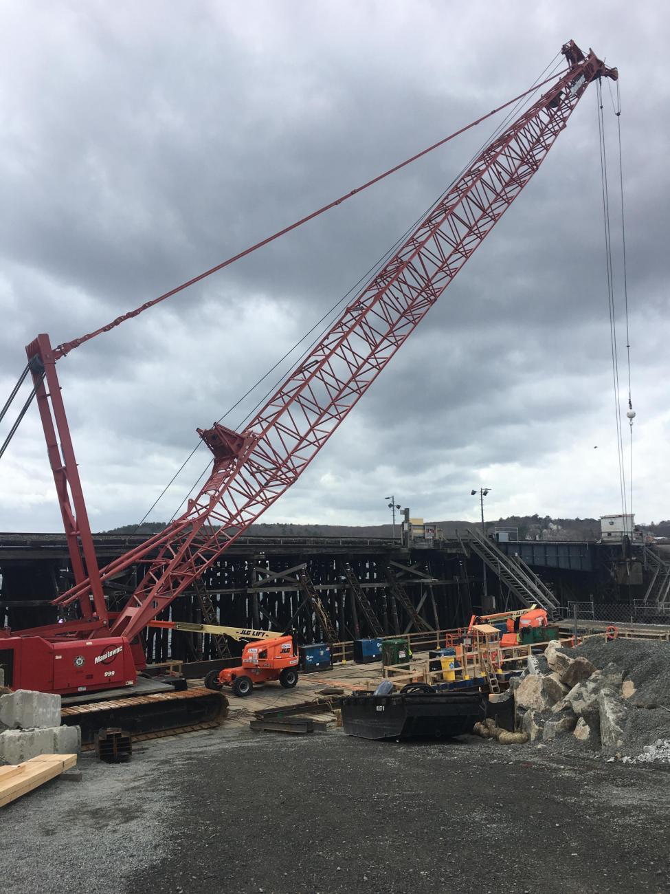 Ground level view of a large red crane at the Gloucester Drawbridge construction site.