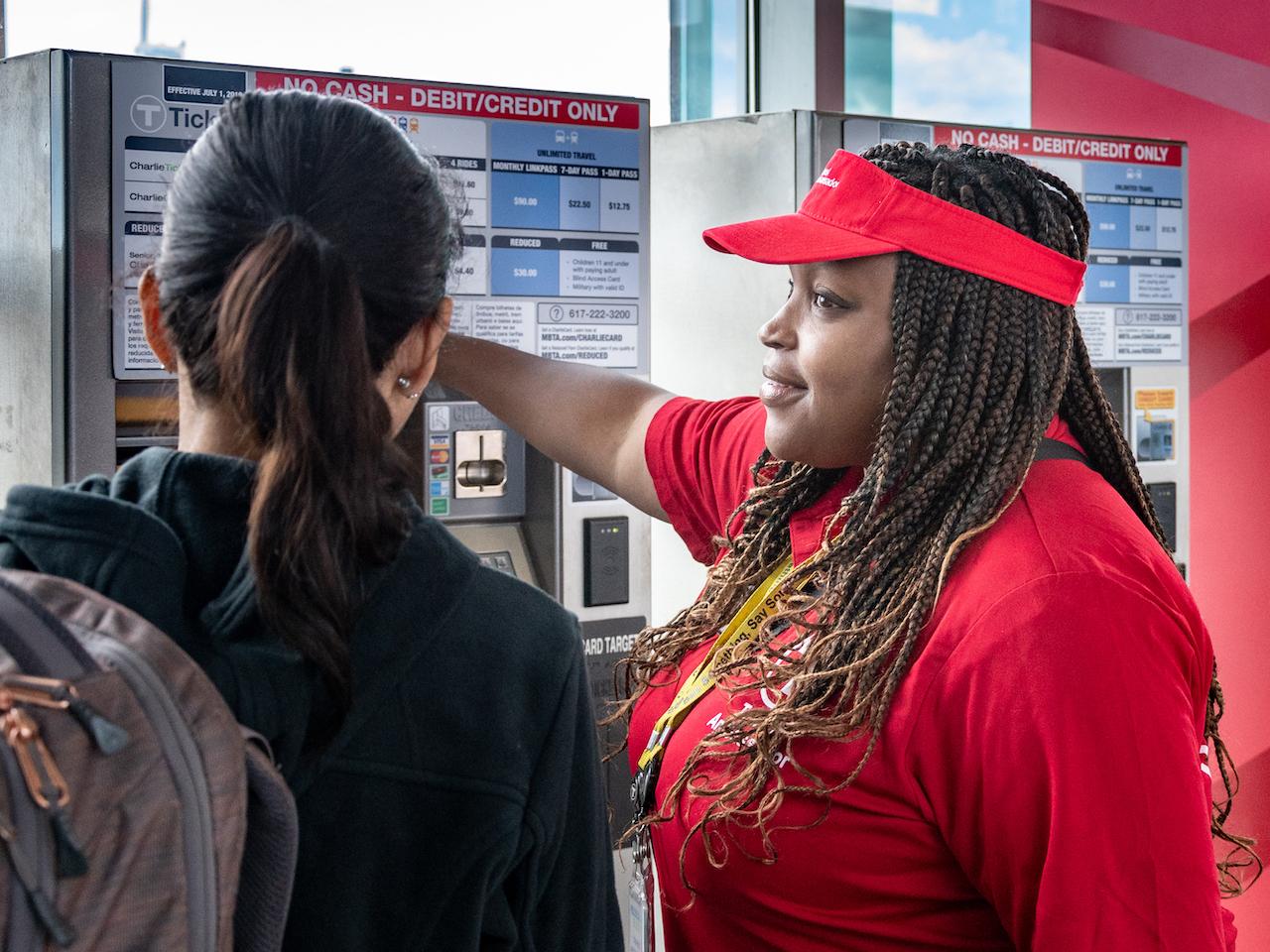 A Transit Ambassadors helps a rider with at fare vending machine at Assembly Station.