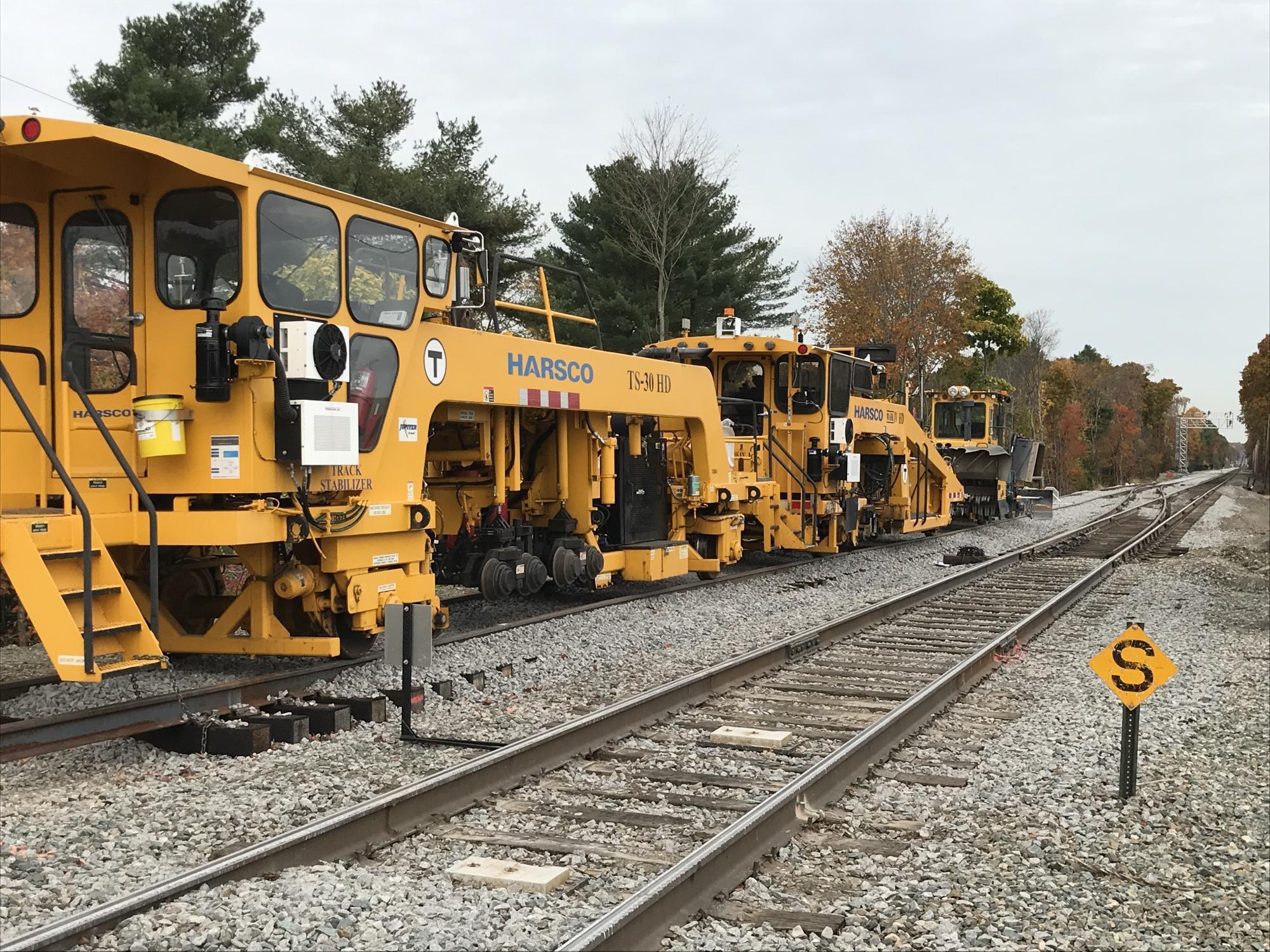 Track surfacing equipment will tamp down the stone ballast and spread it evenly around the tracks
