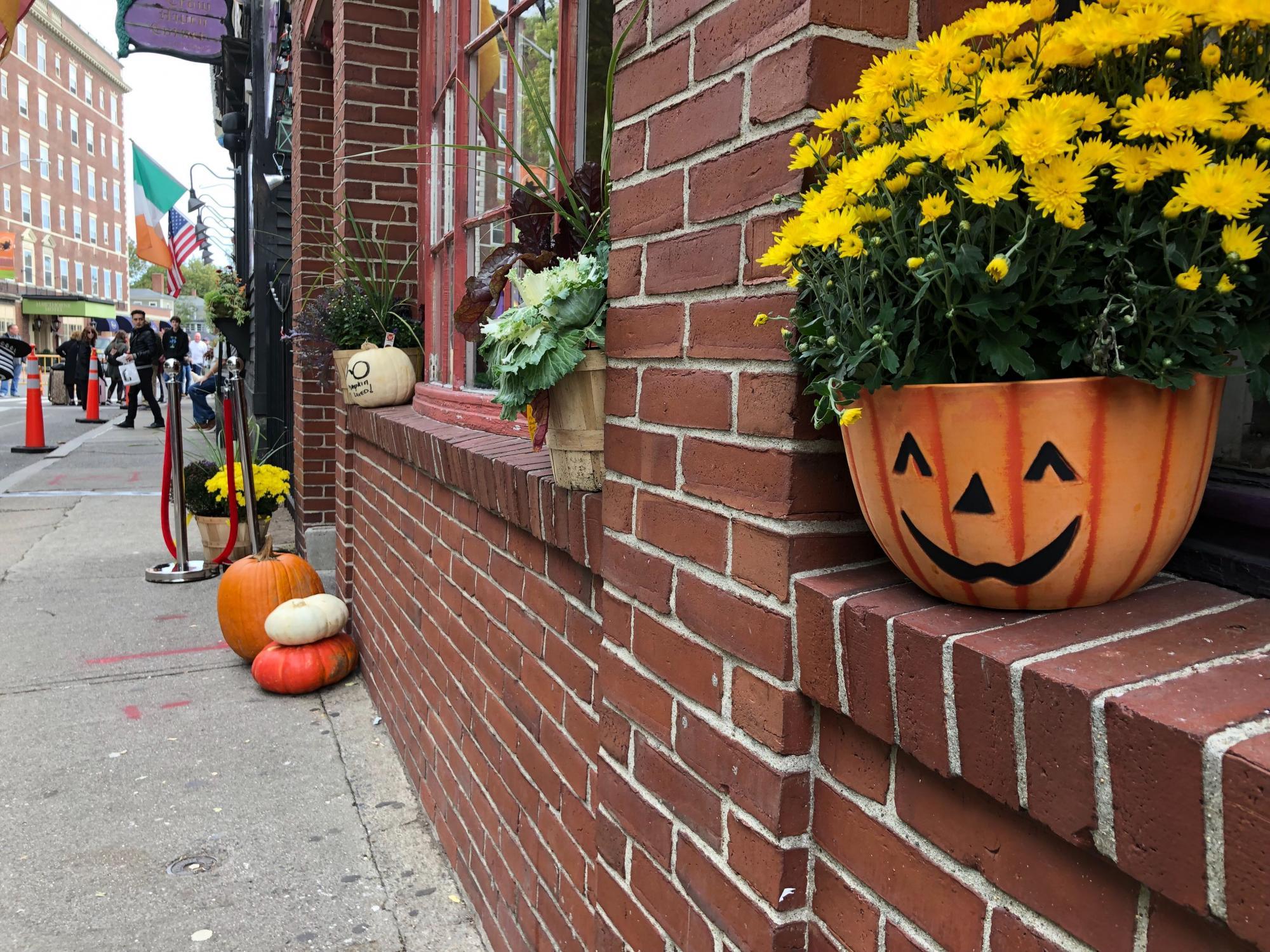 In Salem, a jack-o-lantern planter with flowers sits in a windowsill, with the weekend crowd in the background