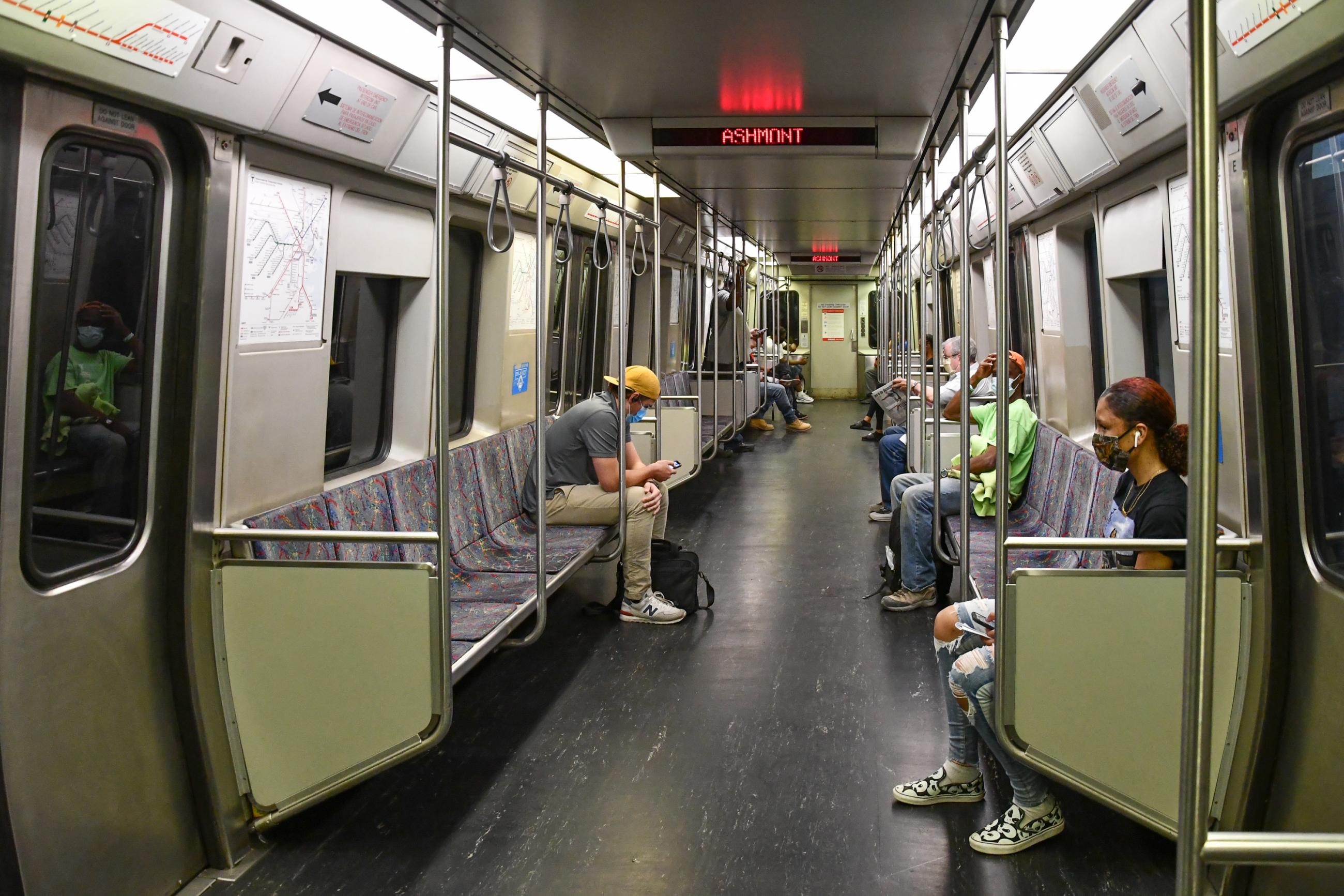 Red Line riders are seated far apart from each other, each wearing a face mask