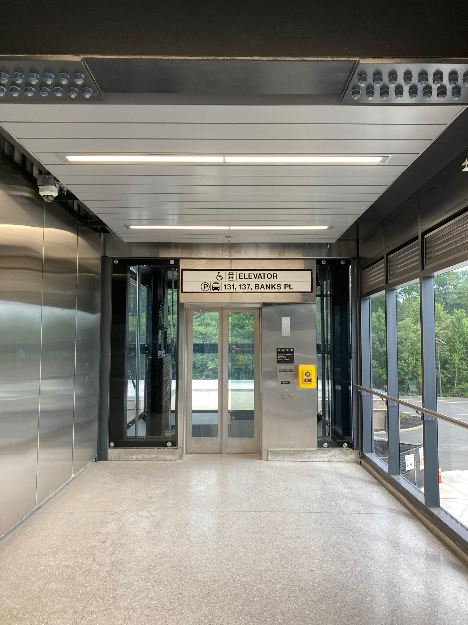 Gray elevator at Oak Grove Station with sign for bus entrance above it 
