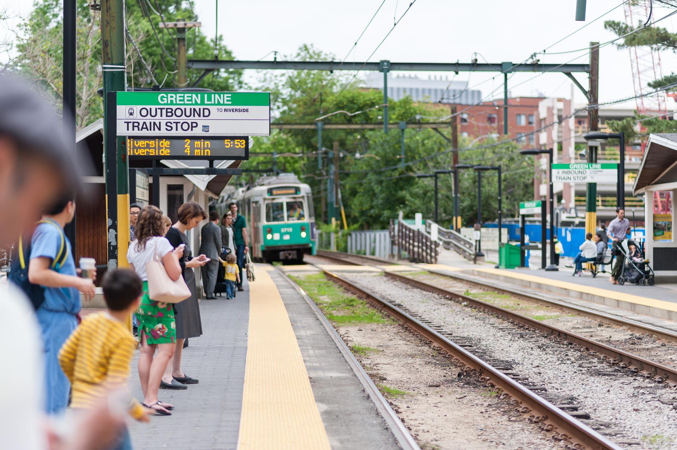 Riders wait on the platform at the Brookline Village stop on the Green Line D branch