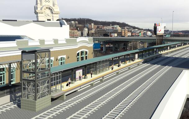 An artist's rendering of how Worcester Union station will look after accessibility improvements have been completed. The station is shown from above with riders waiting on the long platform, which is covered by a long roof.
